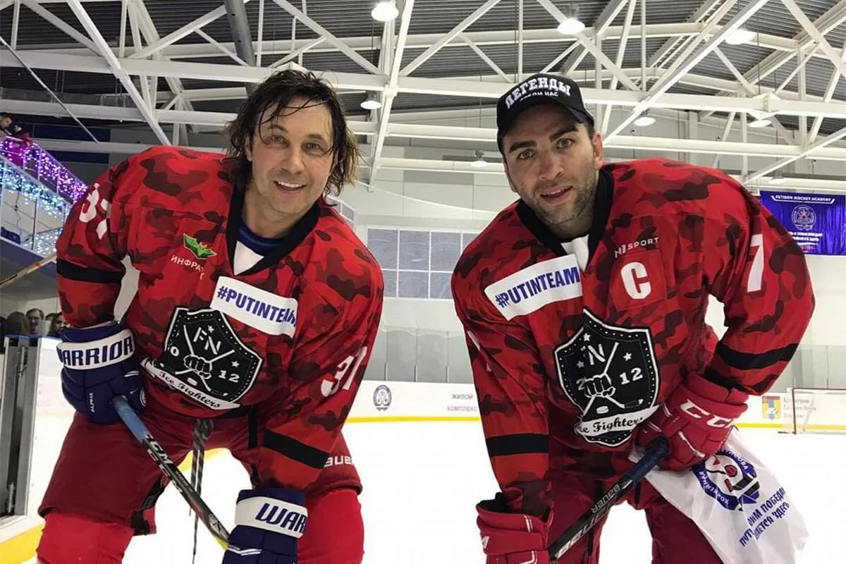 Двое хоккеистов в красных камуфляжных свитерах с меткой N1 SPORT на льду